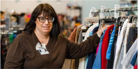 A woman stands near a clothing rack