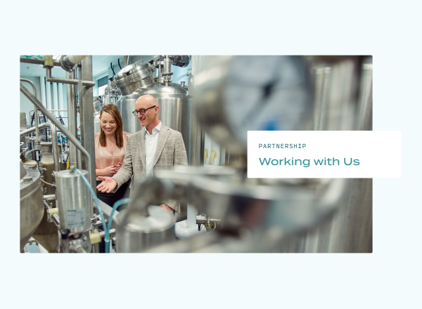 This image shows a headline juxtaposed with a photograph of two people inspecting a biological factory floor.